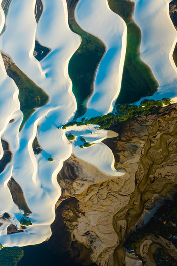 Aerial view of the white sand dunes and turquoise lagoons of Parque Nacional dos Lencois Maranhenses with a winding river and green vegetation in Lencois Maranhenses MA Brazil. Aerial view of the white sand dunes and turquoise lagoons of Parque Nacional dos Lencois Maranhenses with a winding river and green vegetation in Lencois Maranhenses MA Brazil.