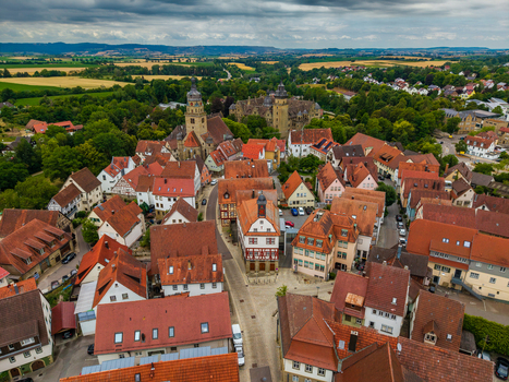 Aerial view of Schloss Neuenstein surrounded by historic red tiled rooftops and lush greenery in the town of Neuenstein Baden Wurttemberg Germany. Aerial view of Schloss Neuenstein surrounded by historic red tiled rooftops and lush greenery in the town of Neuenstein Baden Wurttemberg Germany.
