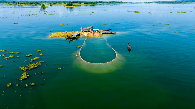Aerial view of fishermen using a large net from wooden boats in the calm waters of Kaptai Lake in Rangamati Chittagong Division Bangladesh.