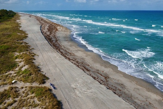 Aerial view of the beach meeting the turquoise waters a serene blend of sand and sea under a soft sky Jupiter Island Florida United States. Aerial view of the beach meeting the turquoise waters a serene blend of sand and sea under a soft sky Jupiter Island Florida United States.