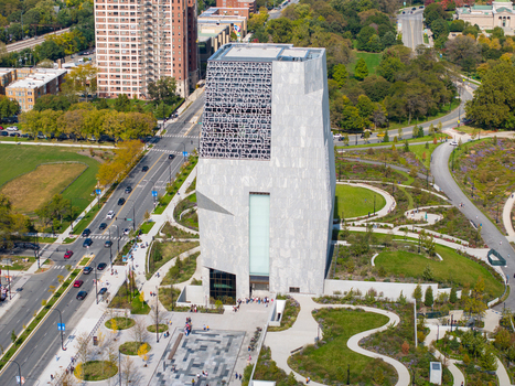 Aerial view of The Obama Presidential Center featuring its modern stone clad tower with intricate facade patterns surrounded by landscaped park grounds and city streets in Chicago Illinois United States. Aerial view of The Obama Presidential Center featuring its modern stone clad tower with intricate facade patterns surrounded by landscaped park grounds and city streets in Chicago Illinois United States.