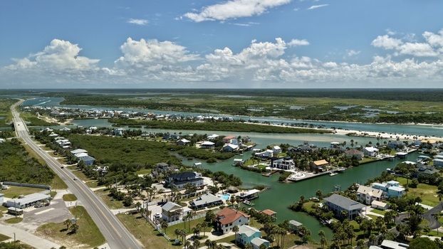 Aerial view of Matanzas Inlet featuring coastal residential houses winding waterways and lush mangroves under a bright blue sky in St. Johns County Florida United States. Aerial view of Matanzas Inlet featuring coastal residential houses winding waterways and lush mangroves under a bright blue sky in St. Johns County Florida United States.