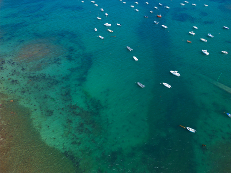 Aerial view of Plage de Port Blanc with numerous small boats anchored in clear turquoise water over a rocky seabed in Penvenan Bretagne France. Aerial view of Plage de Port Blanc with numerous small boats anchored in clear turquoise water over a rocky seabed in Penvenan Bretagne France.
