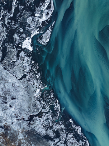 Aerial view of a glacial river with turquoise water and icy sediment patterns flowing through the landscape in Iceland. Aerial view of a glacial river with turquoise water and icy sediment patterns flowing through the landscape in Iceland.