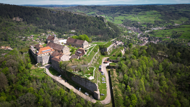 Aerial view of Fort Saint Andre with its historic stone walls and bastions overlooking the lush green hills and valley in Salins les Bains Bourgogne Franche Comte France. Aerial view of Fort Saint Andre with its historic stone walls and bastions overlooking the lush green hills and valley in Salins les Bains Bourgogne Franche Comte France.