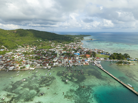 Aerial view of the vibrant coastal village where cerulean waters meet the lush green hills Karimunjawa Central Java Indonesia. Aerial view of the vibrant coastal village where cerulean waters meet the lush green hills Karimunjawa Central Java Indonesia.
