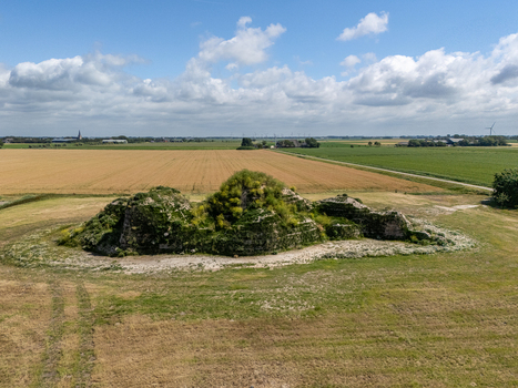 Aerial view of the historic Dijk van een wijf mound covered in lush green vegetation situated amidst expansive agricultural fields under a bright blue sky in Oosterbierum Friesland Netherlands. Aerial view of the historic Dijk van een wijf mound covered in lush green vegetation situated amidst expansive agricultural fields under a bright blue sky in Oosterbierum Friesland Netherlands.