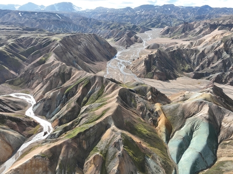 Aerial view of the colorful rhyolite mountains of Landmannalaugar featuring winding glacial rivers rugged volcanic terrain and patches of green moss in Hella Rangarthing ytra Iceland. Aerial view of the colorful rhyolite mountains of Landmannalaugar featuring winding glacial rivers rugged volcanic terrain and patches of green moss in Hella Rangarthing ytra Iceland.