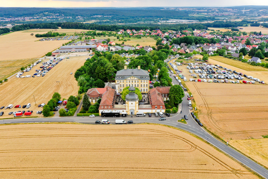 Aerial view of Schloss Jagersburg featuring its yellow facade and central courtyard surrounded by golden wheat fields and parking areas in Eggolsheim Bayern Germany. Aerial view of Schloss Jagersburg featuring its yellow facade and central courtyard surrounded by golden wheat fields and parking areas in Eggolsheim Bayern Germany.