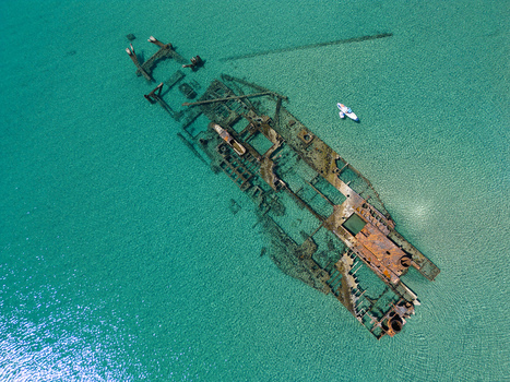Aerial view of the Shipwreck Epanomi submerged in crystal clear turquoise water with a small boat nearby Epanomi Greece.