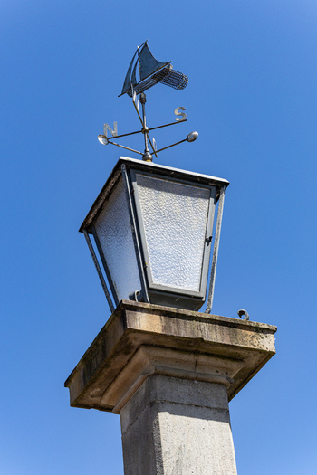 View of Hooksiel lantern and sailing ship weather vane against a clear blue sky in Wangerland Niedersachsen Germany. View of Hooksiel lantern and sailing ship weather vane against a clear blue sky in Wangerland Niedersachsen Germany.