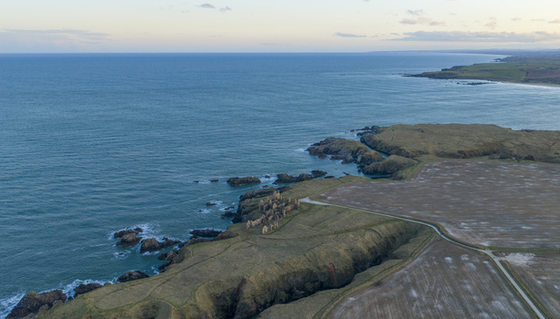 Aerial view of the ruins of Slains Castle perched on rugged cliffs overlooking the North Sea with surrounding grassy fields Cruden Bay Scotland United Kingdom. Aerial view of the ruins of Slains Castle perched on rugged cliffs overlooking the North Sea with surrounding grassy fields Cruden Bay Scotland United Kingdom.
