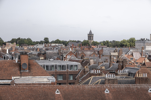 Aerial view of historic rooftops and chimneys of the city center with a church tower in the distance in York England United Kingdom.