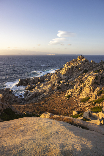View of the rugged granite rock formations of Capo Testa overlooking the turquoise Mediterranean Sea under a clear sunset sky in Capo Testa Sardegna Italy.
