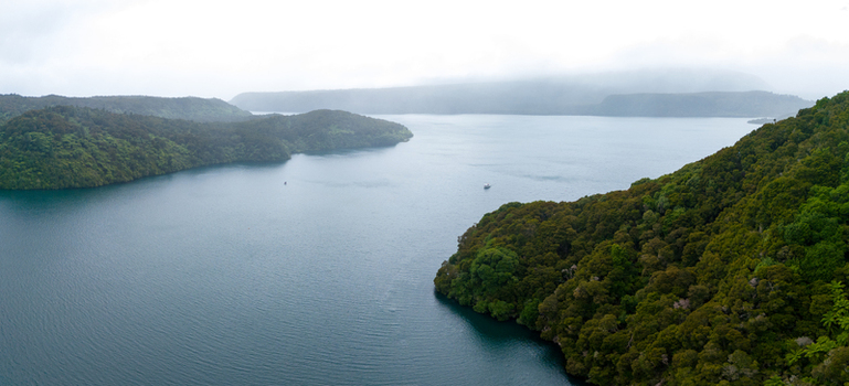 Aerial view of the tranquil lake embraces lush green islands under a misty sky Rotorua Bay of Plenty New Zealand. Aerial view of the tranquil lake embraces lush green islands under a misty sky Rotorua Bay of Plenty New Zealand.