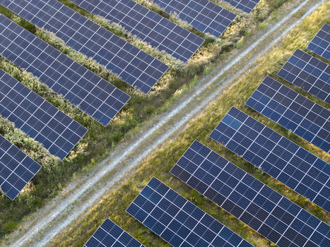 Aerial view of rows of solar panels installed in a field with a dirt path running through the center Poland. Aerial view of rows of solar panels installed in a field with a dirt path running through the center Poland.