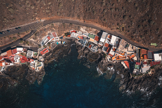 Aerial view of colorful coastal houses nestled along the rocky shoreline and dark blue waters of the Atlantic Ocean in Bocacangrejo Canarias Spain. Aerial view of colorful coastal houses nestled along the rocky shoreline and dark blue waters of the Atlantic Ocean in Bocacangrejo Canarias Spain.