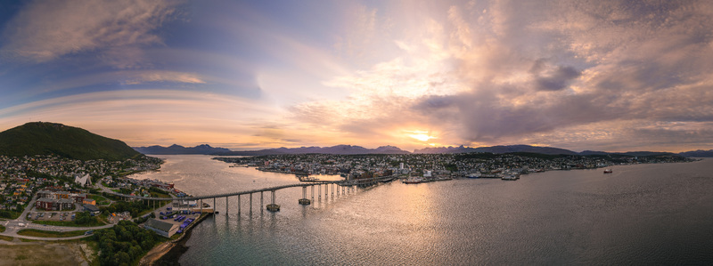 Aerial view of Tromso Bridge connecting the city to the mainland with the Arctic Cathedral visible under a golden sunset sky in Tromso Troms Norway. Aerial view of Tromso Bridge connecting the city to the mainland with the Arctic Cathedral visible under a golden sunset sky in Tromso Troms Norway.