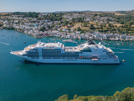 Fowey United Kingdom 10 August 2026 Aerial view of a cruise ship anchored in the Fowey river with the historic town of Fowey and its waterfront buildings in the background. Fowey United Kingdom 10 August 2026 Aerial view of a cruise ship anchored in the Fowey river with the historic town of Fowey and its waterfront buildings in the background.