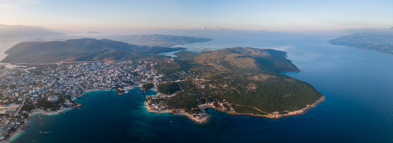 Aerial view of the coastal town of Ksamil with its turquoise bays green peninsulas and white buildings under a soft morning sky in Ksamil Vlore County Albania. Aerial view of the coastal town of Ksamil with its turquoise bays green peninsulas and white buildings under a soft morning sky in Ksamil Vlore County Albania.