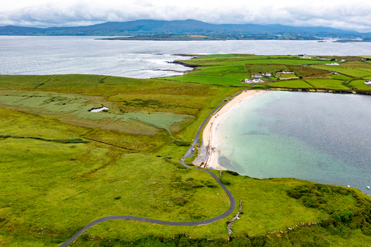 Aerial view of St John s Point Beach with its winding coastal road vibrant green fields and sandy shoreline along the Atlantic coast in Dunkineely County Donegal Ireland.