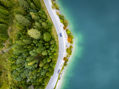 Aerial view of a winding road snaking along the vibrant turquoise Plansee lake embraced by lush green forests Plansee Tyrol Austria. Aerial view of a winding road snaking along the vibrant turquoise Plansee lake embraced by lush green forests Plansee Tyrol Austria.