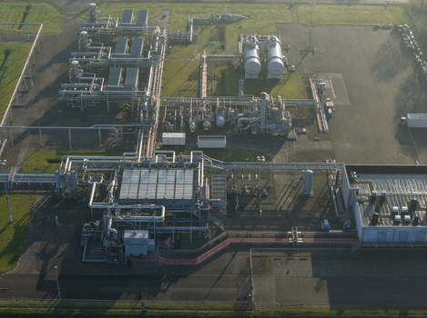 Aerial view of the natural gas mining facility with complex pipelines storage tanks and industrial infrastructure under soft morning light Slochteren Groningen Netherlands. Aerial view of the natural gas mining facility with complex pipelines storage tanks and industrial infrastructure under soft morning light Slochteren Groningen Netherlands.