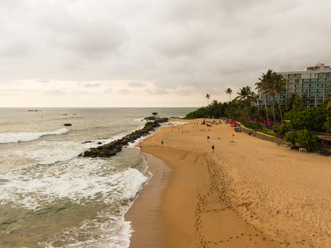 Aerial view of Dadalla beach featuring golden sand crashing waves palm trees and coastal resorts under a cloudy sky Galle Southern Province Sri Lanka. Aerial view of Dadalla beach featuring golden sand crashing waves palm trees and coastal resorts under a cloudy sky Galle Southern Province Sri Lanka.