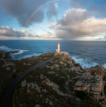 Aerial view of Faro de Punta Nariga lighthouse on a rocky headland with a vibrant rainbow arching over the Atlantic Ocean under a cloudy sky Malpica A Coruna Spain. Aerial view of Faro de Punta Nariga lighthouse on a rocky headland with a vibrant rainbow arching over the Atlantic Ocean under a cloudy sky Malpica A Coruna Spain.