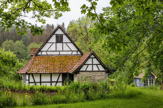 View of Hennebergisches Museum Kloster Vessra with its traditional half timbered architecture and moss covered roof by a pond in Kloster Vessra Thuringen Germany.