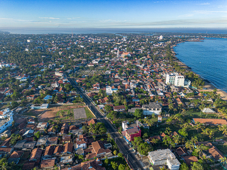 Aerial view of Negombo Beach and the surrounding coastal town with dense rooftops palm trees and the blue Indian Ocean in Negombo Western Province Sri Lanka. Aerial view of Negombo Beach and the surrounding coastal town with dense rooftops palm trees and the blue Indian Ocean in Negombo Western Province Sri Lanka.