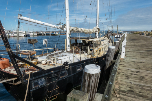 View of a sailboat moored at a wooden pier in the harbor of Block Island with calm water and a clear blue sky in New Shoreham Rhode Island United States.