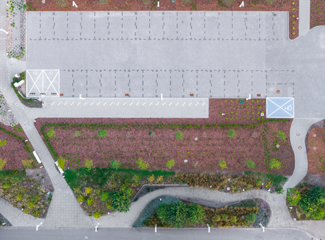 Aerial view of a modern paved parking lot with designated spaces surrounded by landscaped garden beds with trees and shrubs and pedestrian walkways in Sopot Pomeranian Voivodeship Poland. Aerial view of a modern paved parking lot with designated spaces surrounded by landscaped garden beds with trees and shrubs and pedestrian walkways in Sopot Pomeranian Voivodeship Poland.