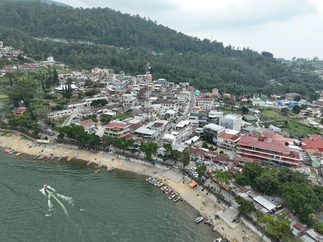 Aerial view of Sarangan Lake with boats docked along the sandy shore a motorboat on the water and the town of Plaosan nestled against lush green hills in Plaosan East Java Indonesia. Aerial view of Sarangan Lake with boats docked along the sandy shore a motorboat on the water and the town of Plaosan nestled against lush green hills in Plaosan East Java Indonesia.