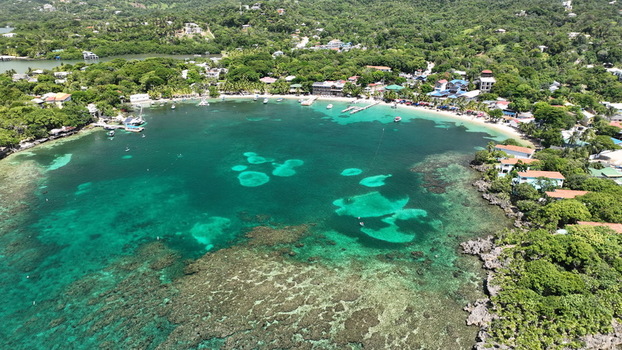 Aerial view of the coastal village with turquoise waters coral reefs and lush tropical vegetation in West End Bay Islands Department Honduras.