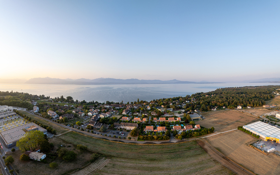 Aerial view of the village of Etoy situated along the shores of Lake Geneva with residential houses green fields and distant mountains in Etoy Vaud Switzerland.