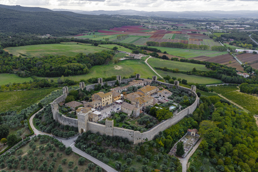 Aerial view of the historic fortified town of Monteriggioni featuring medieval stone walls towers and traditional buildings surrounded by olive groves in Monteriggioni Tuscany Italy.