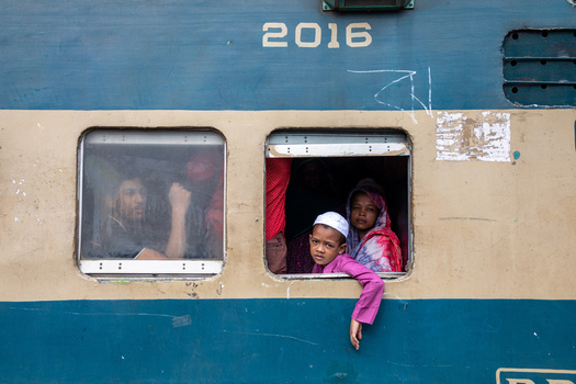 Dhaka Bangladesh 14 June 2018 View of passengers including a young boy and a woman looking out of the windows of a blue train carriage at Airport Railway Station. Dhaka Bangladesh 14 June 2018 View of passengers including a young boy and a woman looking out of the windows of a blue train carriage at Airport Railway Station.