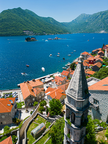 Aerial view of the historic town of Perast with its stone bell tower terracotta rooftops and the blue waters of the Bay of Kotor Perast Kotor Municipality Montenegro. Aerial view of the historic town of Perast with its stone bell tower terracotta rooftops and the blue waters of the Bay of Kotor Perast Kotor Municipality Montenegro.