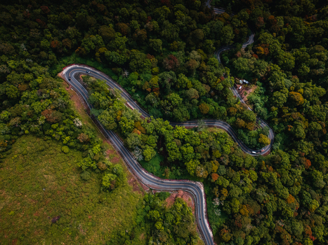 Aerial view of a winding road snaking through a dense forest near the Sembalun agricultural basin at the foothills of Mount Rinjani Sembalun West Nusa Tenggara Indonesia. Aerial view of a winding road snaking through a dense forest near the Sembalun agricultural basin at the foothills of Mount Rinjani Sembalun West Nusa Tenggara Indonesia.