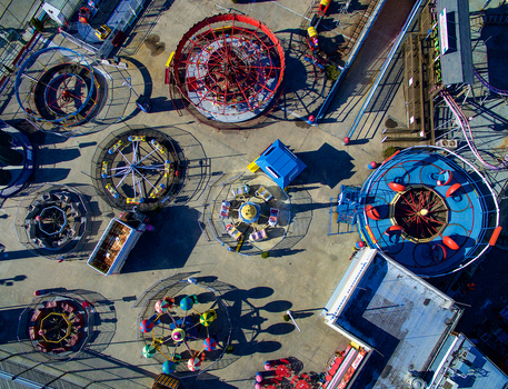 Aerial view of Coney Island amusement park with colorful rides and attractions on a concrete lot with long shadows in Kings County New York United States.