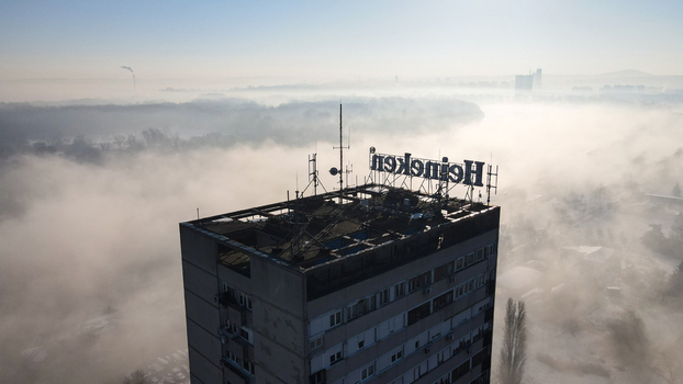Belgrade Serbia 16 January 2022 Aerial view of a tall building with a Heineken sign on the roof surrounded by thick morning fog and mist. Belgrade Serbia 16 January 2022 Aerial view of a tall building with a Heineken sign on the roof surrounded by thick morning fog and mist.