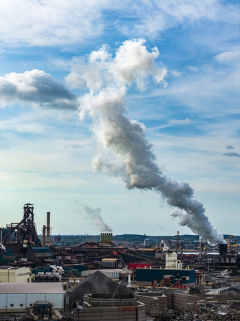 Aerial view of the Tata Steel industrial complex with large smokestacks emitting plumes of smoke over the manufacturing facility in Velsen Noord Noord Holland Netherlands. Aerial view of the Tata Steel industrial complex with large smokestacks emitting plumes of smoke over the manufacturing facility in Velsen Noord Noord Holland Netherlands.