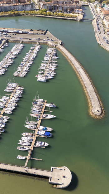 Aerial view of the marina in Zumaia with numerous sailboats and yachts docked at piers along the breakwater in Zumaia Basque Country Spain.