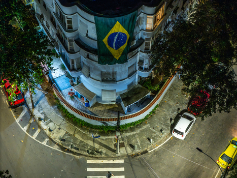 Aerial view of a street corner at night featuring a building with a large Brazilian flag illuminated by streetlights with parked cars in Rio de Janeiro Rio de Janeiro Brazil. Aerial view of a street corner at night featuring a building with a large Brazilian flag illuminated by streetlights with parked cars in Rio de Janeiro Rio de Janeiro Brazil.