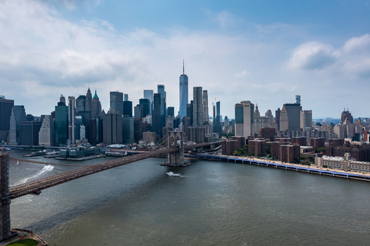New York United States 11 August 2021 Aerial view of the Brooklyn Bridge spanning the East River with the Manhattan skyline and One World Trade Center under a blue sky.