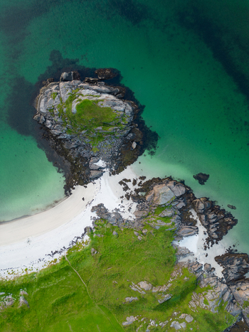 Aerial view of the rocky coastline and white sand beach at Tangstad with turquoise water and lush green hills in Leknes Nordland Norway. Aerial view of the rocky coastline and white sand beach at Tangstad with turquoise water and lush green hills in Leknes Nordland Norway.