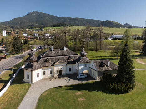 Aerial view of Kastiel Kubinyi manor house with its historic architecture and the Velky Choc mountain peak in the background Vysny Kubin Zilinsky kraj Slovakia.