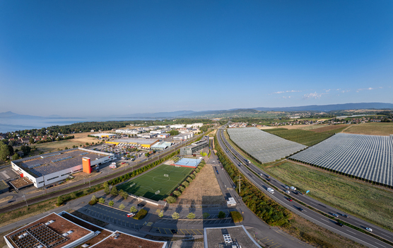 Aerial view of the industrial area greenhouses and a soccer field situated near the highway and Lake Geneva in Etoy Vaud Switzerland.