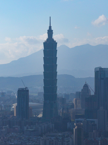 Aerial view of Taipei 101 skyscraper rising above the urban skyline of Taipei City with distant mountains under a clear blue sky Taipei City Taiwan. Aerial view of Taipei 101 skyscraper rising above the urban skyline of Taipei City with distant mountains under a clear blue sky Taipei City Taiwan.